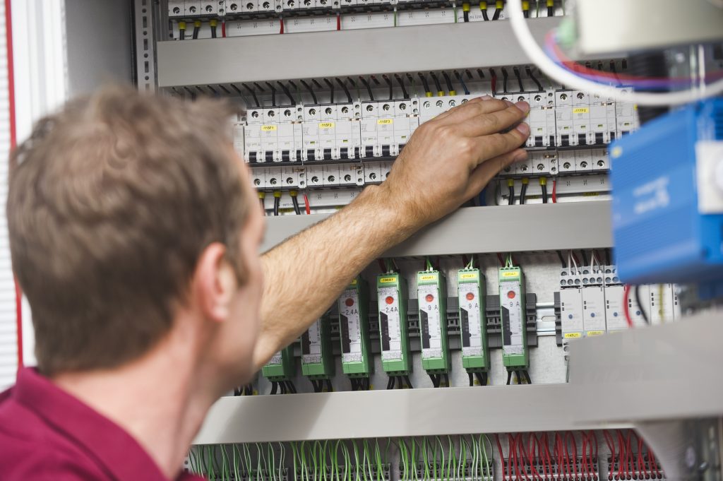 Germany, Munich, Technician checking switch button of circuit board